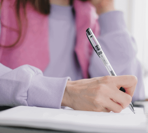 Woman with pink scarf writing in notebook