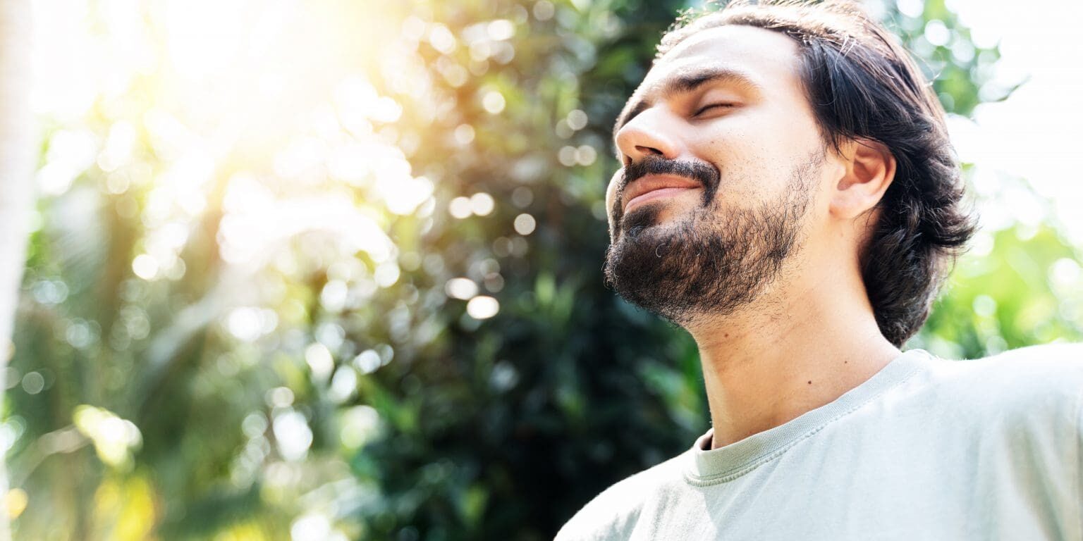 Bearded man looking content with the sun shining